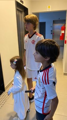 two boys and a girl standing in front of a computer