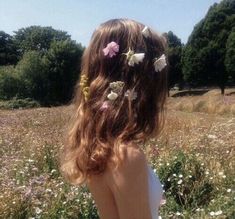 a girl with flowers in her hair standing in a field