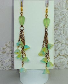 Elegantly designed glass floral fringe earrings.   These beautiful earrings will go with almost anything in your closet, or a friend's.   Look no further, you have just found the perfect girlfriend, sister, or mother's gift.  There has never been a better time to showcase your uniqueness. FIT AND FINISH FOR YOUR PRODUCT Color: Green and gold Size: 4.25" fringe dangle design Material: Glass Beads on Gold Chain   WHAT'S IN THE BOX: 1 pair of earrings. Any other items shown in picture are for staging and to show scale and are not included with purchase. Thank you for visiting my shop! Bohemian Glass Drop Earrings, Wire Wrapped Glass Dangle Earrings, Glass Wire Wrapped Dangle Earrings, Bohemian Glass Dangle Jewelry, Elegant Czech Glass Chandelier Dangle Earrings, Glass Dangle Earrings For Pierced Ears, Unique Glass Dangle Earrings, Perfect Girlfriend, The Perfect Girlfriend