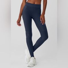 a woman in tight blue leggings and sports bra is posing for the camera