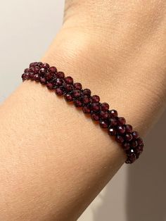 Add a touch of elegance to your outfit with this handmade natural red garnet bracelet.  The faceted garnet stones are hand-knitted onto a black rope to create a unique macrame design.  This bracelet is 16 cm in size, but can be adjusted to your desired size upon request. Not only does this bracelet add a pop of color to your look, it also carries significant meaning.  Garnet is known for symbolizing faith, love, devotion, and trust, as well as balancing out emotional states and promoting passion Luxury Handmade Garnet Jewelry, Elegant Burgundy Bracelets As Gifts, Handmade Elegant Red Crystal Bracelet, Elegant Handmade Red Crystal Bracelet, Elegant Red Crystal Bracelet With Gemstone Beads, Elegant Ruby Beaded Bracelets With Gemstones, Elegant Ruby Gemstone Beaded Bracelets, Adjustable Garnet Gemstone Bracelet, Adjustable Garnet Gemstone Bracelets