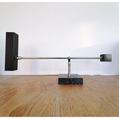 a black square object sitting on top of a wooden table next to a white wall