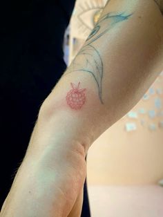 a person with a tattoo on their arm holding a cell phone in one hand and a small pineapple on the other