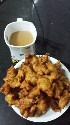 a white plate topped with fried food next to a cup of tea