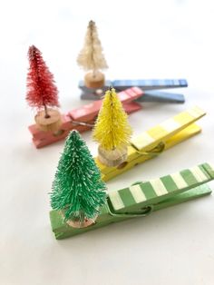 small christmas trees sitting on top of clothes pegs in front of scissors and combs