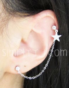 a close up of a person wearing an ear chain with stars and chains attached to it