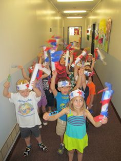 a group of children standing in a hallway with paper hats on their heads and holding toothbrushes