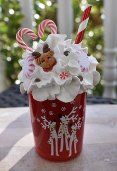 a red cup filled with candy canes and whipped cream on top of a table