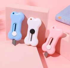 three different colored dog shaped usb devices on a pink surface next to a blue and white book