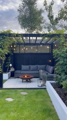 an outdoor living area with couches, tables and lights