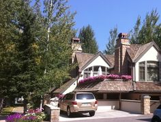 a car is parked in front of a house with flowers on the roof and windows