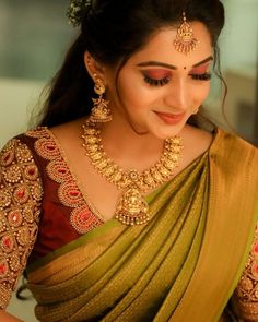 a woman in a green and gold sari with jewelry on her head, looking down at the camera