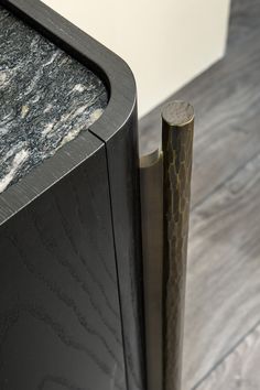 a close up of a black cabinet with marble on the top and metal handle at the bottom