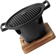 a cast iron skillet sitting on top of a wooden stand with a black lid