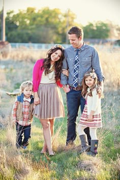 an adult and two children posing for a photo in front of trees with pink flowers