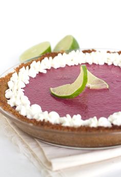 a pie with lime slices on top and whipped cream around the edges, sitting on a plate