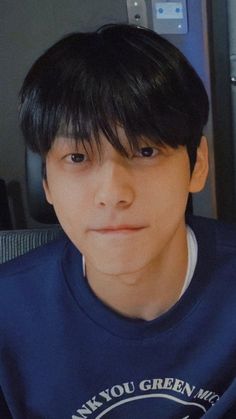 a young man with black hair wearing a blue t - shirt and looking at the camera