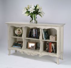 a vase with flowers on top of a book shelf