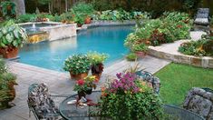 an outdoor swimming pool surrounded by plants and potted flowers on the side of it