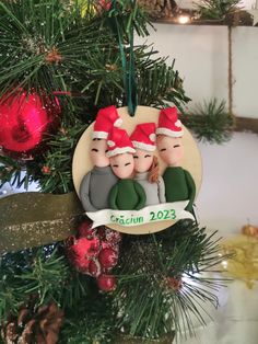 a christmas ornament with three children hanging from it's side on a tree