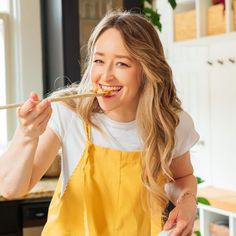 a woman in an apron eating food with a spoon