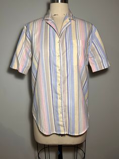 "Pastel vertical stripe golf or tennis shirt. 60/Cotton, 40/Polyester    Size Medium 19\" cross shoulder 42\" bust  43\" sweep 28\" length 19\" sleeve length" Spring Horizontal Stripe Collared Shirt, Relaxed Fit Vertical Stripes Collared Shirt, Classic Short Sleeve Tops With Horizontal Stripes, Short Sleeve Top With Striped Collar For Daywear, Spring Collared Tops With Contrast Stripes, Spring Collared Top With Contrast Stripes, Striped Short Sleeve Tops For Daywear, Fitted Collared Top With Contrast Stripes, Pinstripe Collared Tops For Daywear