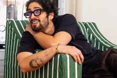 a man sitting on top of a green striped couch