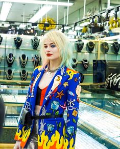 a woman with blonde hair wearing a blue jacket and red top standing in front of a store display