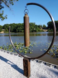 a metal sculpture is in the middle of a pond with water lilies on it