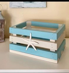 two wooden crates with starfish on them sitting next to a small lantern and clock