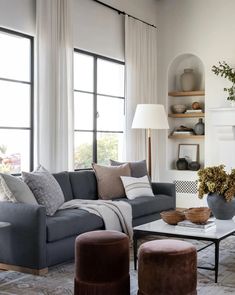 a living room filled with lots of furniture next to a fire place and large windows