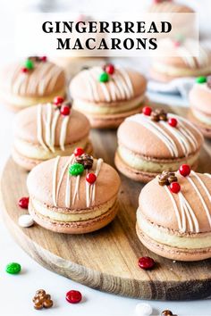 a wooden plate topped with mini gingerbread macarons covered in frosting and candy