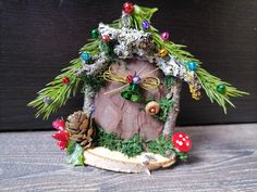 a small house made out of wood and decorated with christmas decorations on the outside, sitting on a wooden surface