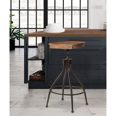 an industrial style bar stool sits in front of a counter with black cabinets and windows