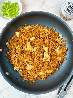 noodles and vegetables are being prepared in a skillet