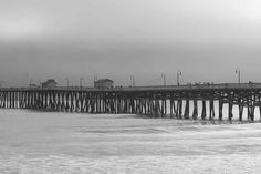 black and white photograph of a pier in the ocean