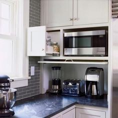 a kitchen with white cabinets and black counter tops, stainless steel appliances and coffee maker