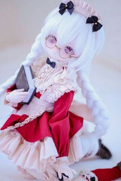 a doll with white hair and glasses holding a book