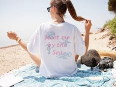 Embrace coastal charm with our vintage inspired seashells Comfort Colors cotton Tshirt. This Cottagecore aesthetic nautical Tee is perfect as an ocean swimsuit coverup or an coastal vacation surf shirt. Featuring a hand drawn textured feel to the text and seashells, this versatile Summer Vacation Mode Beach Shirt is ideal for any sunny adventure. Crafted from soft, breathable cotton, it's a must-have for your summer wardrobe :) Features a front and back design Available colors are: White Ivory B Nautical Beach Tops For Summer, Nautical Tops For Beach In Summer, Nautical Cotton Tops For The Beach, Nautical Style Beach Tops For Summer, Nautical Style Graphic Print Tops For Summer, Nautical Short Sleeve Beach Top, Trendy White Print Beach T-shirt, Beach Graphic Tee With Front Print, Nautical Style Letter Print T-shirt For Summer