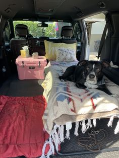 a dog is laying on a blanket in the back of a van with its trunk open