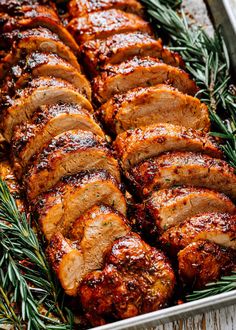 sliced pork roast in a pan with rosemary sprigs