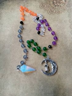 This set of prayer beads was made with Samhain in mind. This set of beads features colorful beads, a gemstone pendulum, and a silver-toned metal charm or charms. These prayer beads can be used as prayer or meditation beads, or for pendulum dowsing. These beads are made with Pagans, Wiccans, Witches, Druids, Heathens, and other Pagan groups in mind, but could be used by anyone who loves and has a deep reverence for the Earth. The beads are hand-wired using silver-toned stainless steel eye pins. T Spiritual Necklaces With 8mm Beads For Rituals, 8mm Pearl Beads Spiritual Necklace, Spiritual Silver Crystal Necklace With 8mm Beads, Spiritual Crystal Necklaces With Moon Charm For Festivals, Handmade Crescent Crystal Necklace With Spiritual Style, Handmade Spiritual Crescent Crystal Necklace, Handmade Black Spiritual Beads, Handmade Spiritual Czech Glass Crystal Necklace, Affordable Hand-strung Spiritual Beaded Necklaces