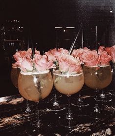 three wine glasses with flowers in them sitting on a marble counter top next to each other