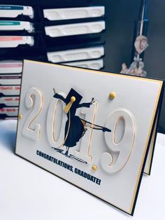 a graduation card with a graduate's cap and gown on it in front of stacks of folders