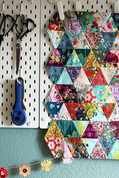 scissors are hanging on the pegs next to a colorful quilt and crafting supplies