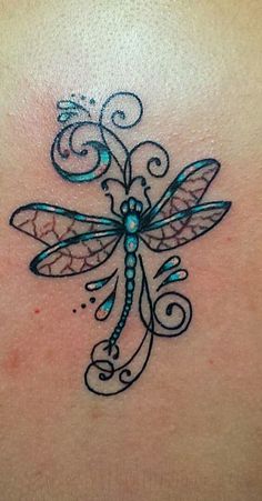 a dragonfly tattoo on the back of a woman's shoulder