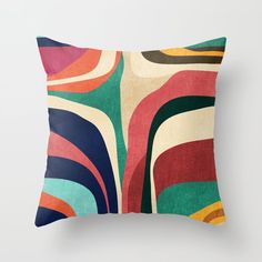 a colorful pillow with an abstract design on the front and back, sitting against a white wall