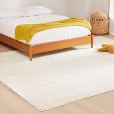 a bed sitting on top of a wooden floor next to a white rug