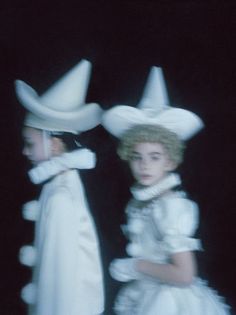 two women in white dresses and hats standing next to each other