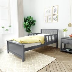 a bedroom with a gray bed frame and yellow pillow on the top of it, next to a white rug